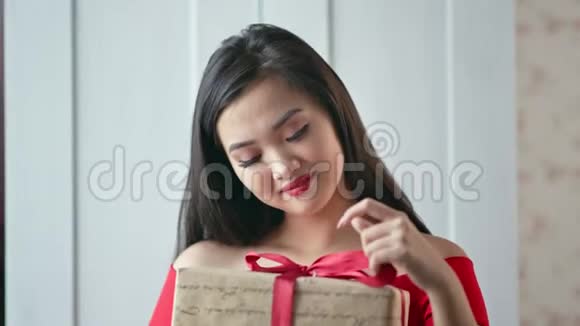 微笑的亚洲年轻女子手持红丝带礼盒的肖像视频的预览图