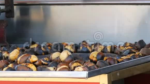 男售货员在一条城市街道上做烤栗子街上的食物热熟的栗子视频的预览图