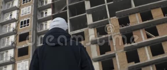 戴白色头盔的建筑工人监督多层建筑的施工进度视频的预览图
