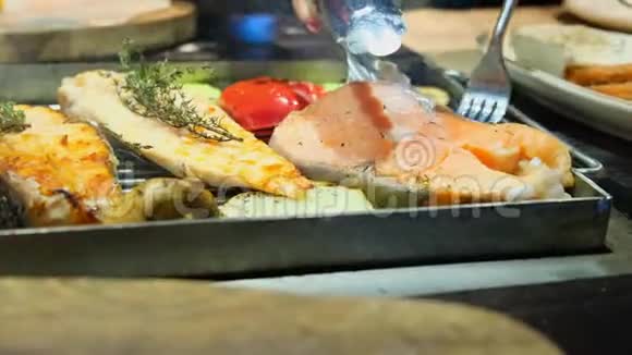 烤鱼烤三文鱼牛排鸡肉芳香香料和烤蔬菜牛排用叉子翻转靠近视频的预览图