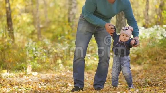 父亲牵着一个小孩子的手在秋天的公园里慢动作视频的预览图