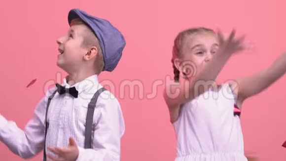 快乐的孩子跳跃在粉色背景上玩心形纸屑视频的预览图