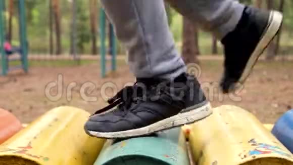 穿着运动鞋的男孩在操场上的跑步机上露天跑步视频的预览图