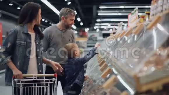 幸福的家庭妈妈爸爸和可爱的孩子正在大超市里挑选食物指着塑料容器说话视频的预览图