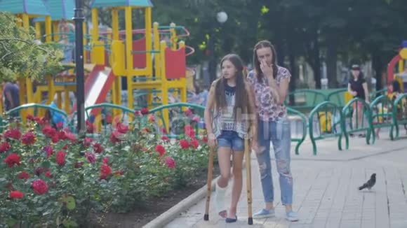 妈妈拄着拐杖用断腿扶着女儿走在街上视频的预览图