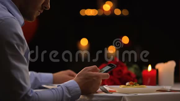 在智能手机上滚动的餐厅里等待约会的男性女士独处时间视频的预览图