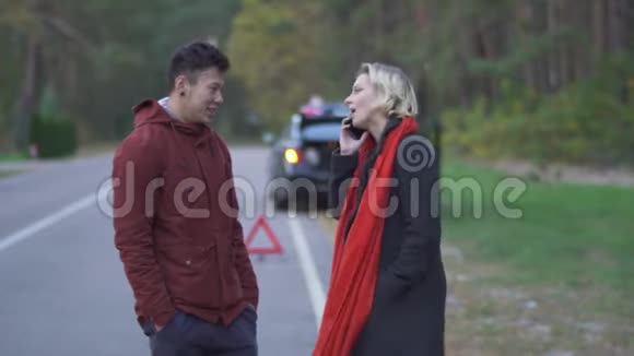 一对年轻夫妇站在路边停着一辆车的背景上金发美女在说话视频的预览图