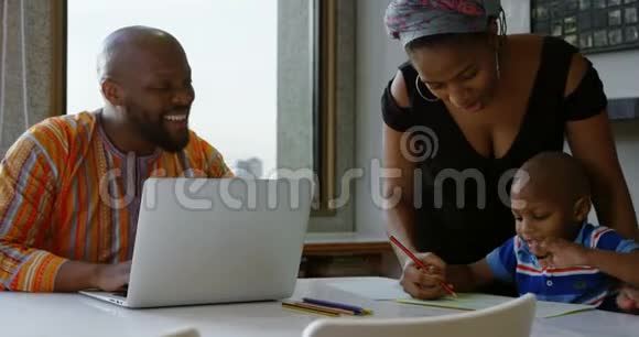 母亲和儿子在家里桌子上的一张纸上画素描视频的预览图