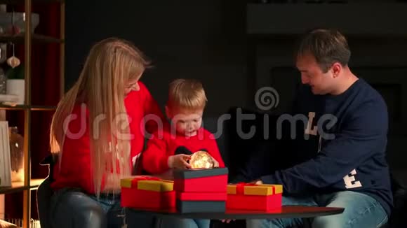 准备圣诞庆祝活动的幸福家庭母亲父亲和孩子在家里打开礼物时微笑着交谈视频的预览图