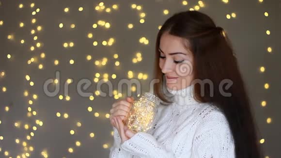 新年圣诞节美丽的女人穿着温暖的白色毛衣手里拿着一盏灯闭上眼睛梦见了视频的预览图
