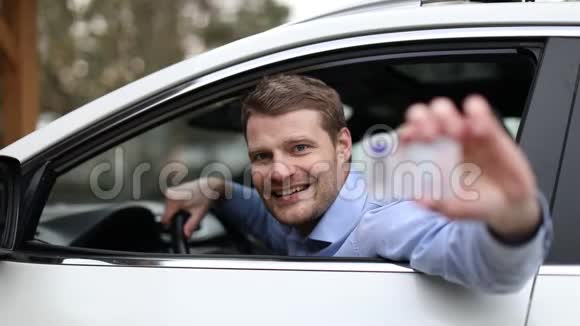 一个微笑的年轻人坐在车里出示他的新驾照视频的预览图