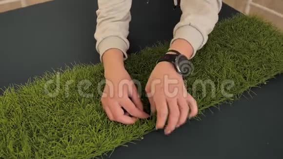 女孩手上拿着一个钟钉在地板上的人造草皮上特写少女双手视频的预览图