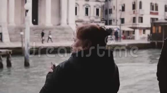 后景兴奋活跃的老白种人旅游妇女在一次冈多拉远足威尼斯旅行上拍摄智能手机照片视频的预览图