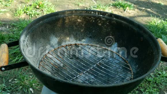 在阳光明媚的夏日人们把煤放在金属烤架或烧烤中燃烧室外视频的预览图