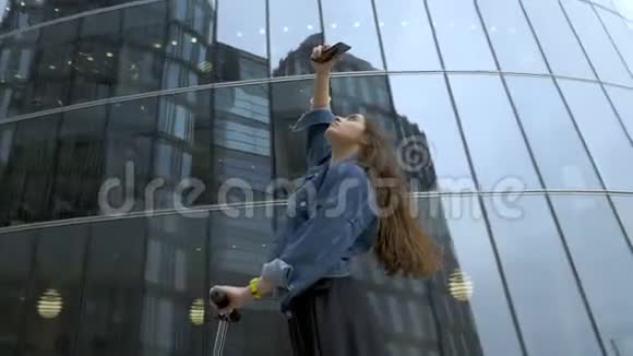 可爱的游客用智能手机相机拍摄未来主义商业中心的照片视频的预览图
