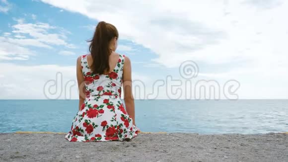 一个漂亮的年轻漂亮的女孩坐在海港的码头上视频的预览图
