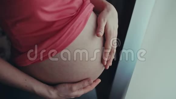一个小女孩在等孩子幸福的孕妇在家摸肚子怀孕的肚子准妈妈视频的预览图