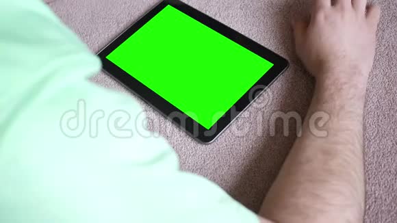 一名白人男性在客厅里听绿色屏幕平板音乐视频的预览图