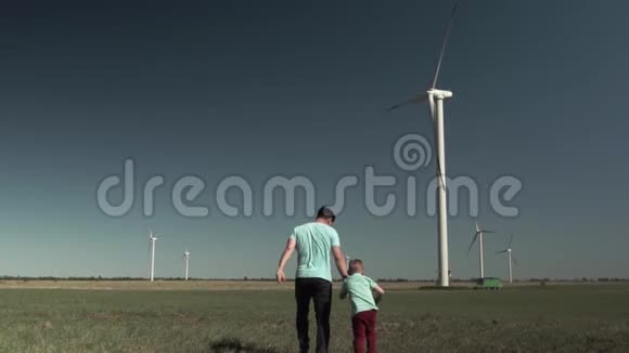 后视父子一起在风车的背景上奔跑视频的预览图