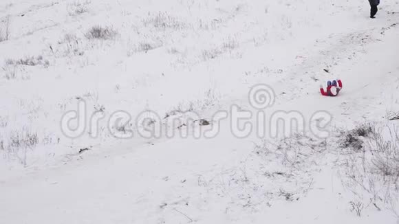 女孩骑在白色的雪山上失去了他们的帽子圣诞节假期冬季运动会慢动作视频的预览图