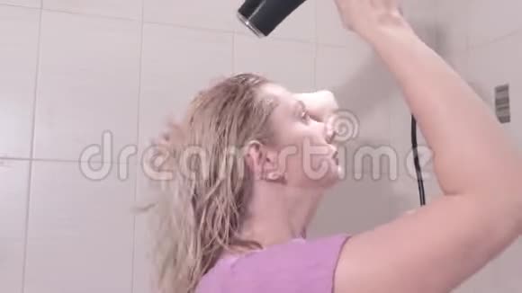 中年金发女人在浴室里用吹风机吹干头发视频的预览图