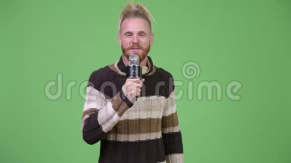 穿着暖和的衣服唱着麦克风的快乐英俊的胡子男人视频的预览图