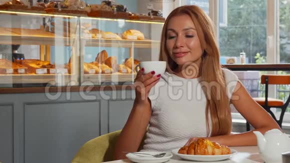 可爱的红头发女人在早晨享受咖啡和牛角面包视频的预览图