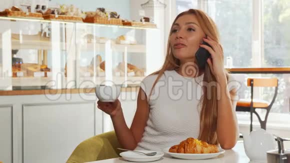 年轻女子看起来很兴奋一边喝咖啡一边打电话视频的预览图