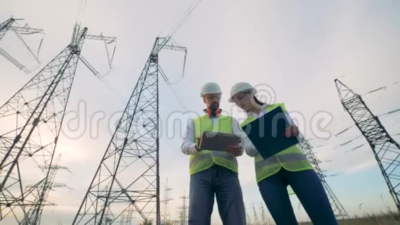 两名电工协同作业站在现场靠近输电线路4K视频的预览图