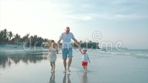 幸福的父亲女儿和儿子在日落时在海滩上玩和玩动作缓慢幸福家庭视频的预览图