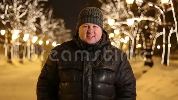 冬天的城市街道上一个晚上穿黑色衣服的英俊胖子的肖像视频的预览图