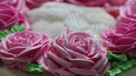 白色蛋糕上粉红色玫瑰和绿叶黄油霜的旋转视频的预览图