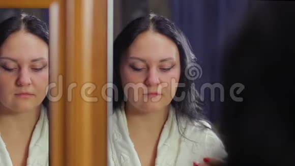 一个穿着白色外套的年轻女人在镜子前用化妆刷做眼妆视频的预览图