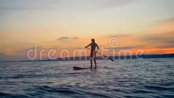 日落景观与一个女人划桨通过开放的水暑假旅游理念视频的预览图