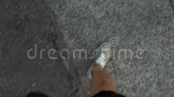 一个男人穿着棕色运动鞋在沥青上行走从上面看视频的预览图