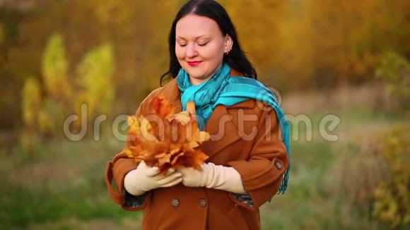 公园秋天的一位年轻女子欣赏一束枫叶慢动作视频的预览图
