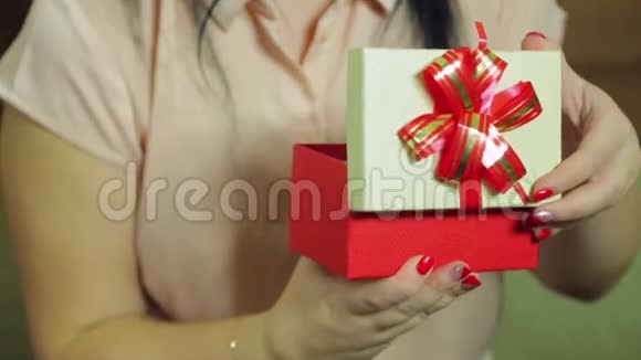一个年轻的女人打开一个盒子里面有一个圣诞礼物她很高兴视频的预览图