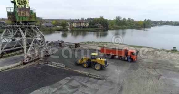 挖土机在港口装载一辆卡车在卡车里装载材料视频的预览图
