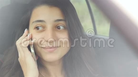 很漂亮的女孩坐在车里打电话她脸上挂着美丽的微笑特写视频的预览图