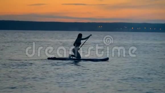 年轻迷人的女人站在膝盖上沿着海岸线划水自由概念视频的预览图