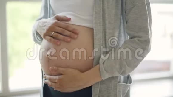 孕肚和嫩妈妈的特写双手用爱和呵护抚摸婴儿的凹凸快乐视频的预览图