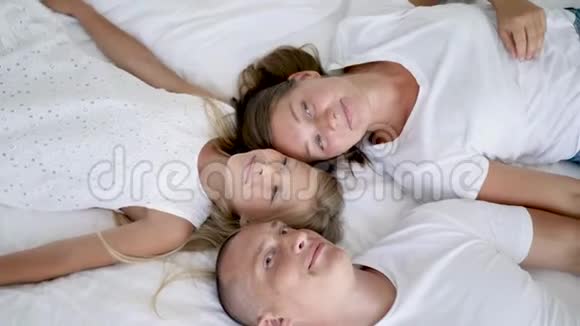 有两个孩子的家庭躺在白色大床上视频的预览图