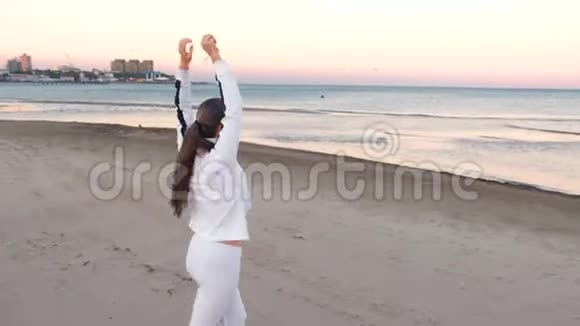 年轻女子正在做运动以恢复呼吸在沙滩上日出在秋天后景视频的预览图