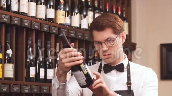 优雅的葡萄酒销售商在一家葡萄酒商店里拿着一瓶葡萄酒和阅读标签视频的预览图