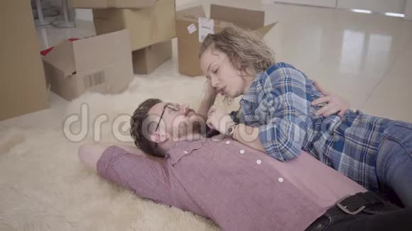 戴眼镜的长胡子男人和卷发的漂亮女人躺在蓬松的地毯上近距离交谈未包装视频的预览图