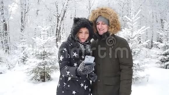 年轻的幸福夫妇是在雪地森林里拍摄的自拍冬季旅行概念视频的预览图