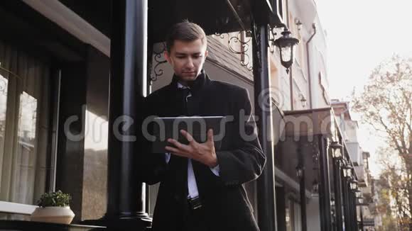 穿西装穿黑色外套的年轻人使用数码平板电脑视频的预览图