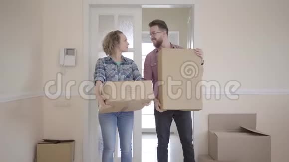 快乐的男人和女人穿着休闲装手里拿着盒子站在房间里已婚夫妇搬进了一个新家视频的预览图