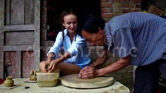 师傅带着快乐的女孩在店里做陶罐视频的预览图