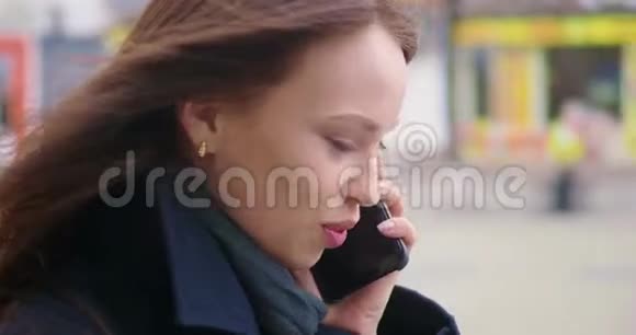 秋天的时候女人在街上散步时打电话特写镜头视频的预览图
